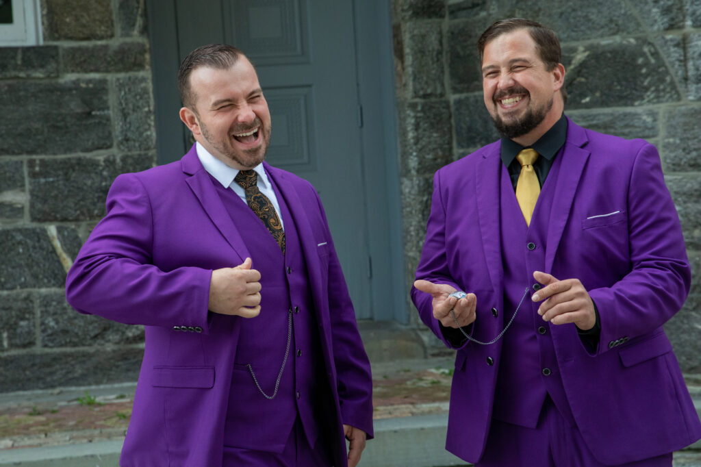 A groom in a purple suit laughs with besst an and brother also in purple suit during photos at the Mamaroneck Beach Club Westchester Wedding Photographer