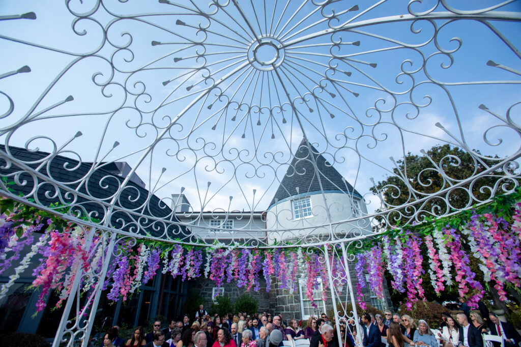 Strands of pink and purple flowers adorn a white wrought iron gazebo at the Mamaroneck Beach Club Westchester Wedding Photographer