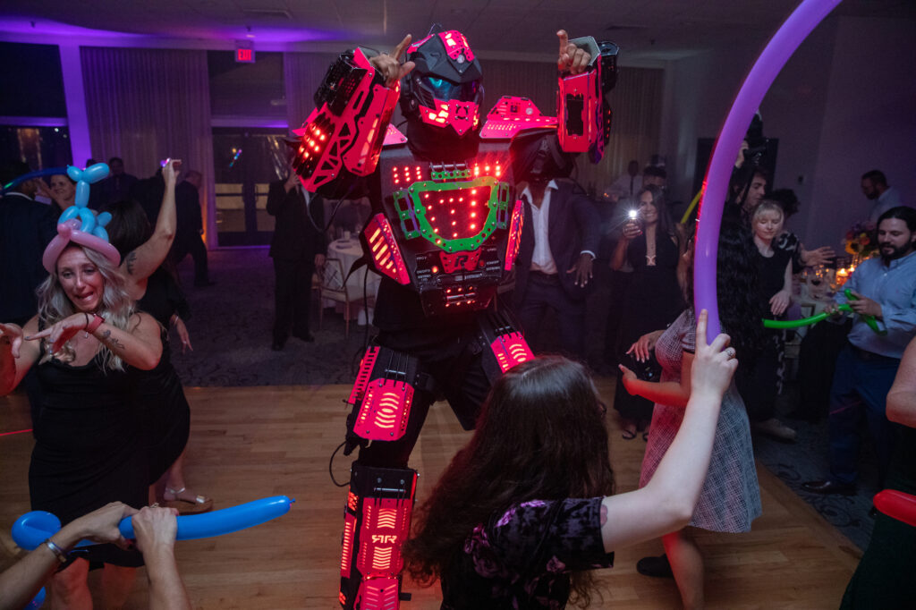 A glowing red and green robot dances with gusts at the Mamaroneck Beach Club reception Westchester wedding Photographer Milestone Images