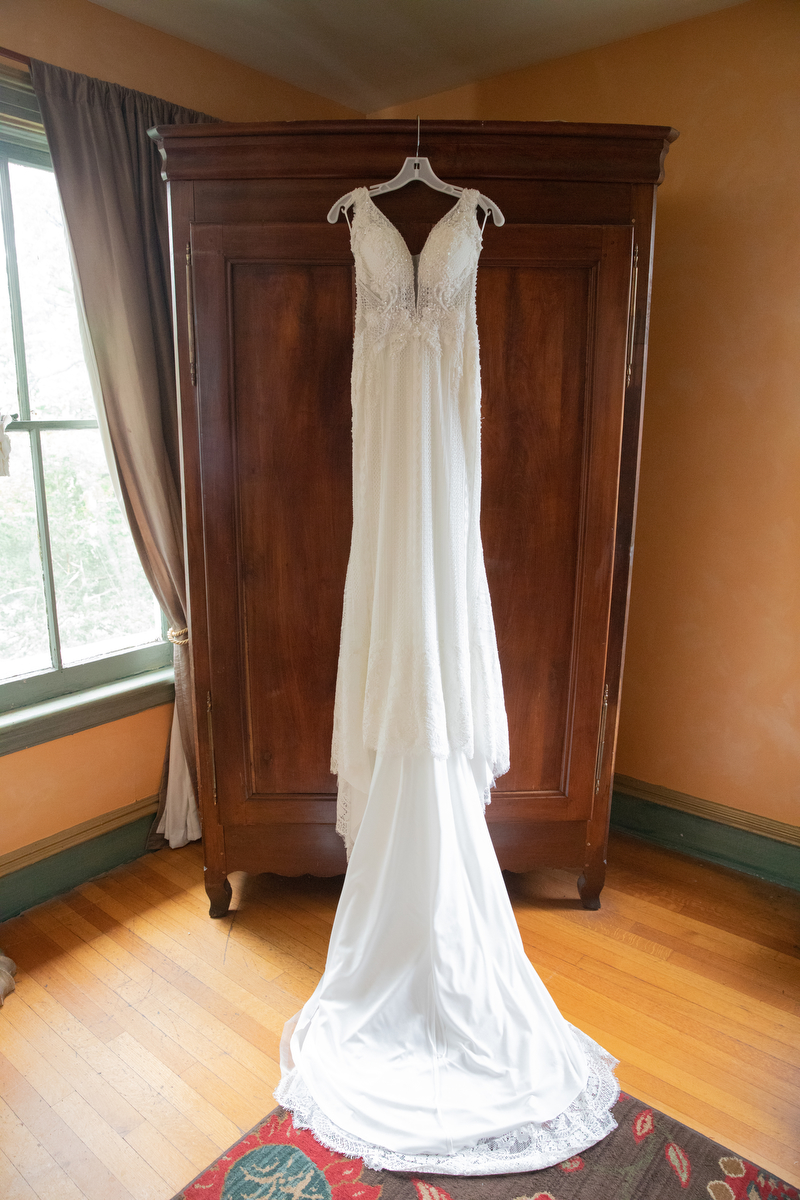 A wedding dress hangs in front of an armoire Rockland County wedding photographer Milestone Images